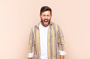 Genç adam agresif bir şekilde bağırıyor, çok kızgın, hayal kırıklığına uğramış, öfkeli ya da sinirli görünüyor.