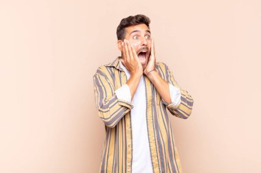 Genç adam mutlu, heyecanlı ve şaşırmış hissediyor, iki eli yüzü yana bakıyor.