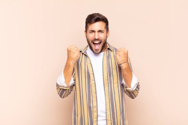 Genç adam muzaffer bir şekilde bağırıyor, gülüyor, mutlu ve heyecanlı hissediyor.