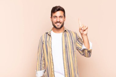 Genç adam mutlu ve mutlu bir şekilde gülümsüyor, tek eliyle boşluğu dolduruyor.