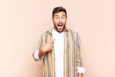 Şok olmuş ve ağzı açık, kendini işaret eden genç bir adam.