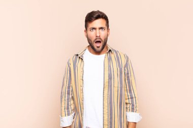 Genç adam şok olmuş, kızgın, sinirli ya da hayal kırıklığına uğramış, ağzı açık ve öfkeli görünüyor.