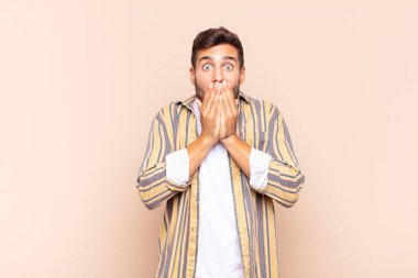 Genç adam endişeli, üzgün ve korkmuş hissediyor, elleriyle ağzını kapatıyor, endişeli ve berbat görünüyor.