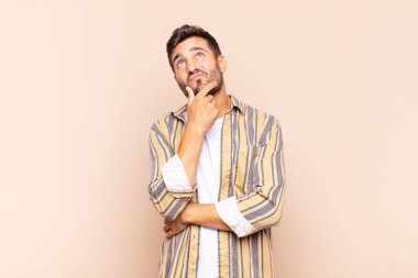 Genç adam düşünüyor, kuşkulu ve şaşkın hissediyor, farklı seçeneklerle, hangi kararı vereceğini merak ediyor.