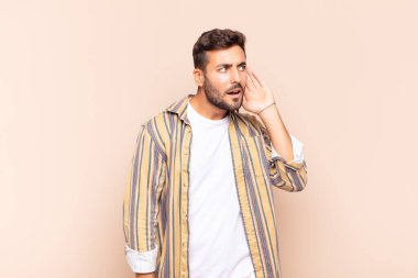 Genç adam ciddi ve meraklı görünüyor, dinliyor, gizli bir konuşma ya da dedikodu duymaya çalışıyor, gizlice dinliyor.