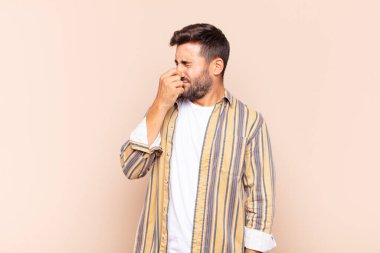 Delikanlı iğreniyor, pis ve nahoş bir koku duymamak için burnunu tutuyor.