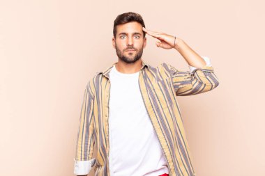 Genç adam, saygı göstererek, onur ve vatanseverlik adına askeri bir selamlama ile kamerayı selamlıyor.