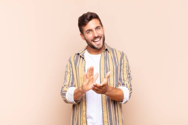 Genç adam mutlu ve başarılı hissediyor, gülümsüyor ve alkışlıyor, alkışlarla tebrik ediyor.