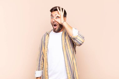 Genç adam şaşkın, şaşırmış ve şaşırmış hissediyor. Elinde şaşkın, inançsız bir bakışla gözlük tutuyor.