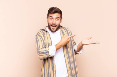 Genç adam neşeyle gülümsüyor ve bir objeyi göstererek veya reklamını yaparak avucundaki kopyalama alanını işaret ediyor.