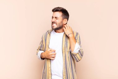 Genç adam stresli, hayal kırıklığına uğramış ve yorgun, endişeli ve sorunlu bir bakışla boynunu ovalıyor.