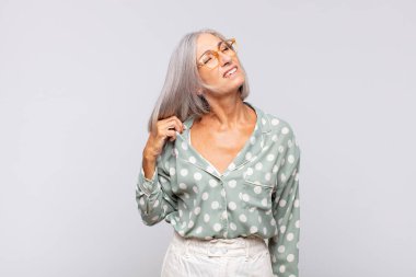 Gri saçlı kadın stresli, endişeli, yorgun ve hayal kırıklığına uğramış, gömleğini çekmiş, sorunlu görünüyor.