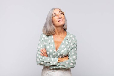 Gri saçlı kadın mutlu, gururlu ve umutlu, merak eden ya da düşünen, çapraz kollarla fotokopi çekmek isteyen