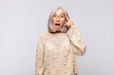 Gri saçlı kadın şaşırmış, ağzı açık, şok olmuş, yeni bir düşünce, fikir ya da konsept keşfediyor.