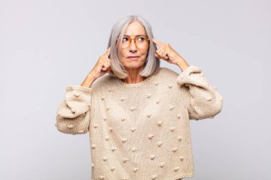 Gri saçlı kadın konsantre olmuş ve bir fikir üzerinde kafa yoruyor, bir soruna ya da soruna bir çözüm hayal ediyor.