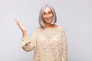 Gri saçlı kadın kendini mutlu, şaşırmış ve neşeli hissediyor, olumlu bir tavırla gülümsüyor, bir çözüm ya da fikir buluyor.