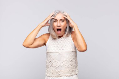 Gri saçlı kadın dehşete kapılmış ve şok olmuş hissediyor, ellerini havaya kaldırıyor ve bir hata yüzünden panikliyor.