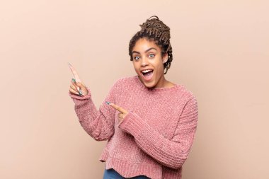 Genç afro kadın şaşkın ve şaşkın bir bakışla kendini işaret ediyor. Seçildiğine şaşırmış ve şaşırmış.