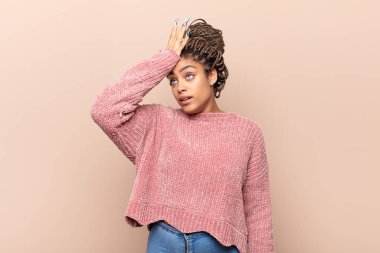 young afro woman raising palm to forehead thinking oops, after making a stupid mistake or remembering, feeling dumb
