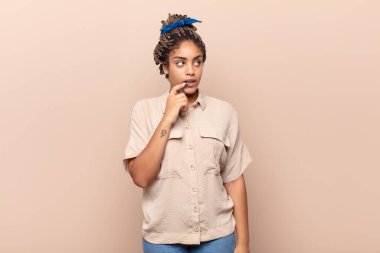 Şaşırmış, gergin, endişeli ya da korkmuş bakışları olan genç afro kadın fotokopi alanına doğru yan bakıyor.