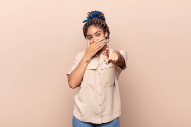 Genç afro kadın sana gülüyor, kamerayı gösteriyor ve seninle dalga geçiyor ya da alay ediyor.