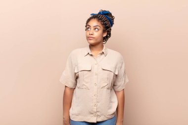 Endişeli, kafası karışık, budala bir ifadeyle afro genç bir kadın, kopya alanı arıyor, şüpheci