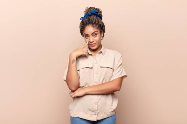 Genç afro kadın sana göz kulak oluyor, güvenmiyor, izliyor, tetikte ve tetikte.