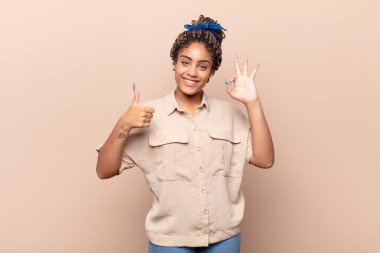 Genç afro kadın kendini mutlu, şaşkın, tatmin olmuş ve şaşırmış hissediyor.