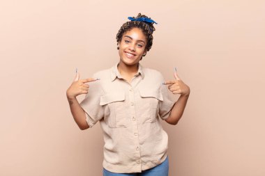 Genç afro kadın gururlu, kibirli, mutlu, şaşırmış ve tatmin olmuş görünüyor.