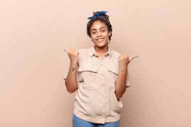 Genç afro kadın neşeyle gülümsüyor ve mutlu görünüyor, kaygısız ve pozitif hissediyor.