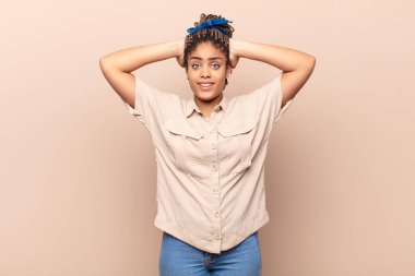 Genç afro kadın kendini stresli, endişeli, endişeli ya da korkmuş hissediyordu. Elleri başının üstünde, hatayla panikliyordu.