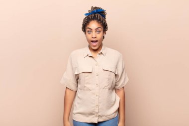 Genç afro kadın şok olmuş ya da şaşırmış görünüyor, ağzı açık bir şekilde 