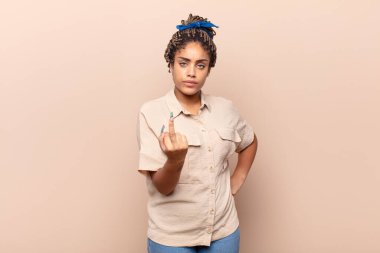 Genç afro kadın kızgın, sinirli, asi ve agresif hissediyor, orta parmağını hareket ettiriyor, karşı koyuyor.