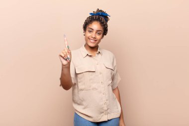 Genç afro kadın gülümsüyor ve arkadaş canlısı görünüyor, bir numara veya ilk eli önde, geriye doğru sayıyor.