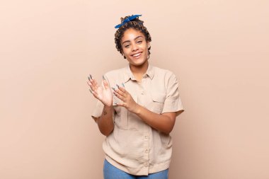 Genç afro kadın kendini mutlu ve başarılı hissediyor, gülümsüyor ve alkışlıyor, alkışlarla tebrik ediyor.