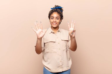 Genç afro kadın gülümsüyor ve arkadaş canlısı görünüyor, 8 ya da 8 numarayı gösteriyor, elleri önde, geriye doğru sayıyor.