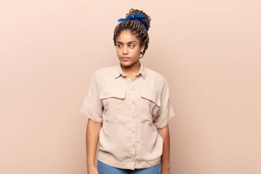 Genç afro kadın üzgün, üzgün ya da kızgın ve olumsuz bir tavır takınıyor, anlaşmazlık içinde kaşlarını çatıyor