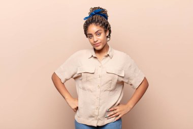 Genç afro kadın gururlu, kendinden emin, havalı, küstah ve küstah görünüyor, gülümsüyor, başarılı hissediyor.