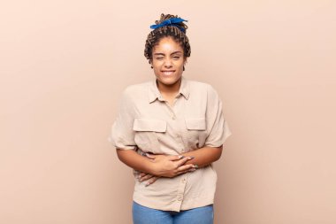 Genç afro kadın endişeli, hasta, hasta ve mutsuz hissediyor. Ağrılı bir mide ağrısı ya da grip geçiriyor.