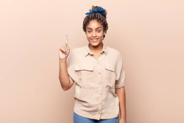 Genç afro kadın mutlu bir şekilde gülümsüyor, tek eliyle uzayı işaret ediyor.