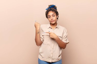 Genç Afro kadın sabırsız ve kızgın görünüyor, saati gösteriyor, dakiklik istiyor, zamanında gelmek istiyor.