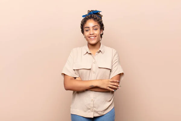 young afro woman looking like a happy, proud and satisfied achiever smiling with arms crossed