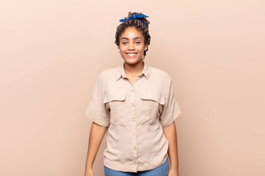 Genç afro kadın mutlu ve şapşal görünüyor. Geniş, eğlenceli, deli gülüşü ve gözleri açık.