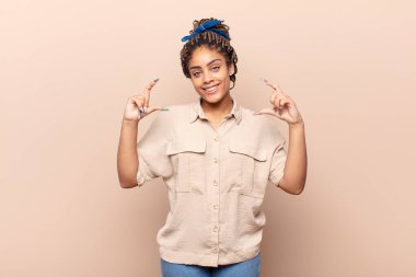 Genç afro kadın kendi gülüşünü çiziyor, iki eliyle, pozitif ve mutlu görünüyor, sağIık kavramı