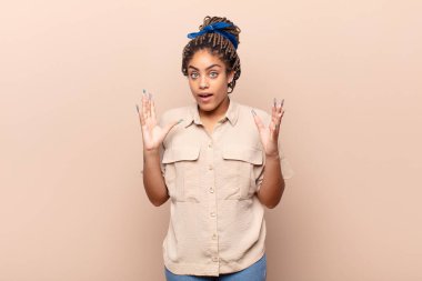 Genç afro kadın şok olmuş ve şaşkın bakıyor, inanılmaz bir şey fark ettiğinde çenesi şaşkın şaşkın