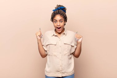 Genç afro kadın mutlu, şaşırmış ve gururlu hissediyor, bağırıyor ve başarıyı büyük bir gülümsemeyle kutluyor.