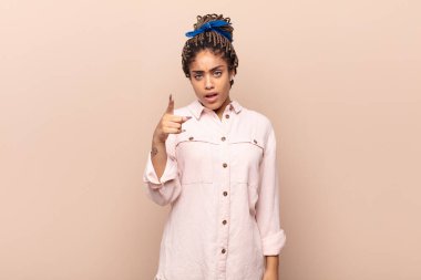 Kızgın, çılgın bir patrona benzeyen sinirli bir ifadeyle kameraya bakan genç bir afro kadın.