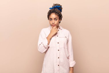 Genç afro kadın ciddi görünüyor, kafası karışık, kararsız ve düşünceli, seçenekler ya da seçimler arasında şüpheci