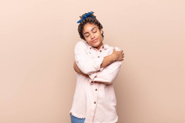 Genç afro kadın aşık, gülümseyen, sarılan ve kendine sarılan, bekar, bencil ve benmerkezci.