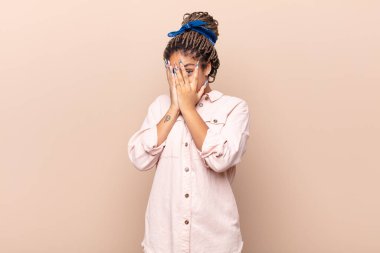 Genç afro kadın korkmuş ya da utanmış hissediyordu. Gözleri yarı kapalı ya da elleri kapalı dikizliyordu.